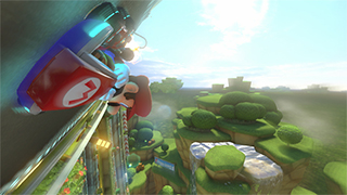 Mario in his kart, on a track that's almost upside-down, with a forest far below. Detail is still cartoony, but much higher resolution.